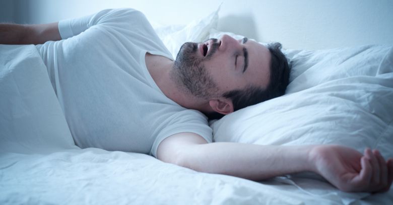 Person experiencing sleep apnea with interrupted breathing and loud snoring during the night