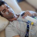 Patient undergoing polysomnography sleep study test with monitoring sensors for sleep apnea diagnosis