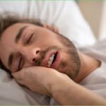 Person snoring due to summer heat and humidity affecting breathing during sleep